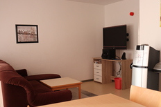 Bild zeigt ein das Wohnzimmer eines der Selbststängigenhäuser. Zu sehen ist die Sofaecke mit Tisch und Fernseher