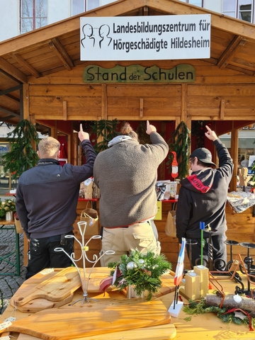 Die Bilder zeigen den Stand der Schulen und drei jungen Auszubildende, adventliche Gestecke aus der Gärtnerei, Vogelhäuschen, Engel und Wichtel aus der Holzwerkstatt und Malerei.