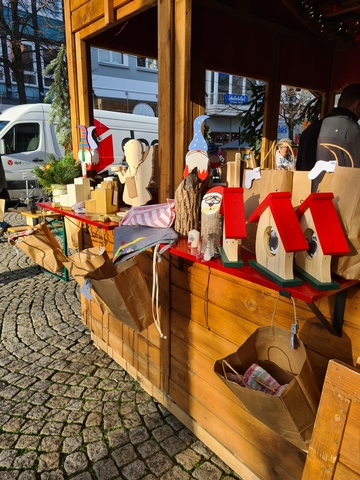 Die Bilder zeigen den Stand der Schulen und drei jungen Auszubildende, adventliche Gestecke aus der Gärtnerei, Vogelhäuschen, Engel und Wichtel aus der Holzwerkstatt und Malerei.