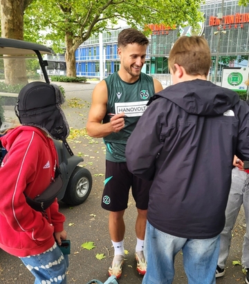 Bild zeigt: Zwei Schüler treffen Enzo Leopold vor dem Stadion