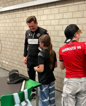 Bild zeigt Trainer Christian Titz im Gespräch mit einer Schülerin und einem Schüler