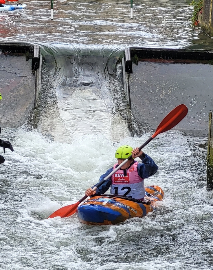 Auf diesem Bild zu sehen sind bunte Kanus und Kanuten, beim Einstieg in das Kanu an der Kanustrecke auf der Innerste in Hildesheim, bei der Abfahrt auf der Welle.