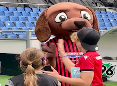 Pressekonferenz und Buchvorstellung bei Hannover 96 - Bild zeigt das Maskottchen EDDI mit einer Schülerin und einem Schüler im Stadion