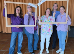 Das Bild zeigt fünf Kolleginnen des LBZH die hinter einem Holzrahmen posieren und mit der Gestik eines geflexten Bizeps Stärke zeigen.